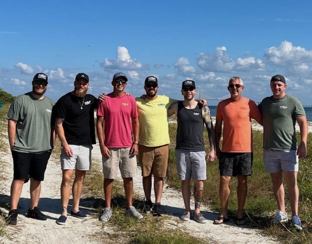 group of men in athletic gear posing for a photo at the beach